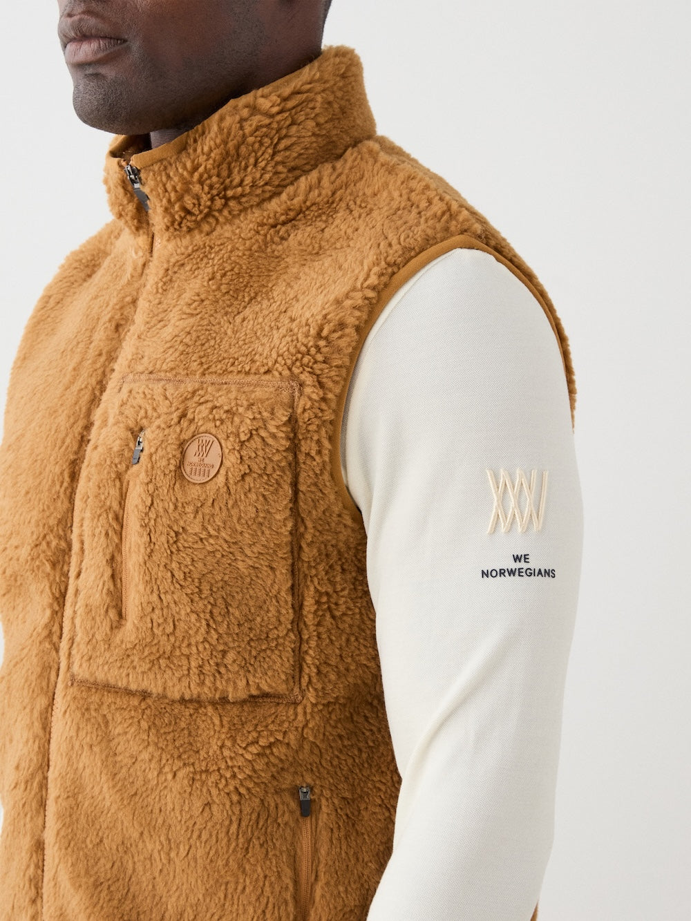 We Norwegians | FW25 | Mens Kebnekaise Vest_Cinnamon | Model wearing this fleece vest with front zipper opening, zipped chest pocket and side pockets - over an off-white top | Shot against an off-white background | Close-up