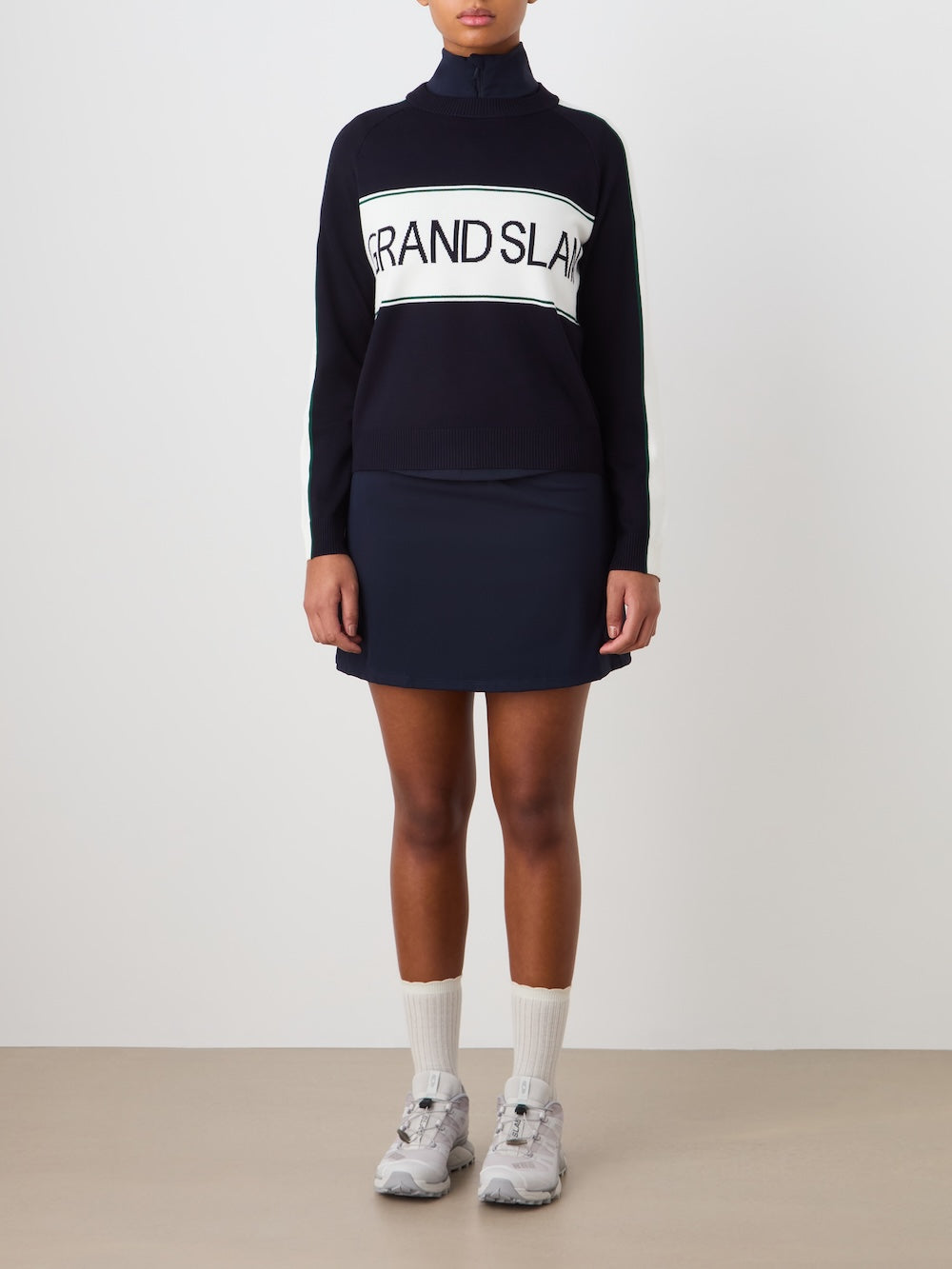 Person wearing a navy blue sweater with "Grand Slam" text in the front, teamed with a navy blue skirt against a light background